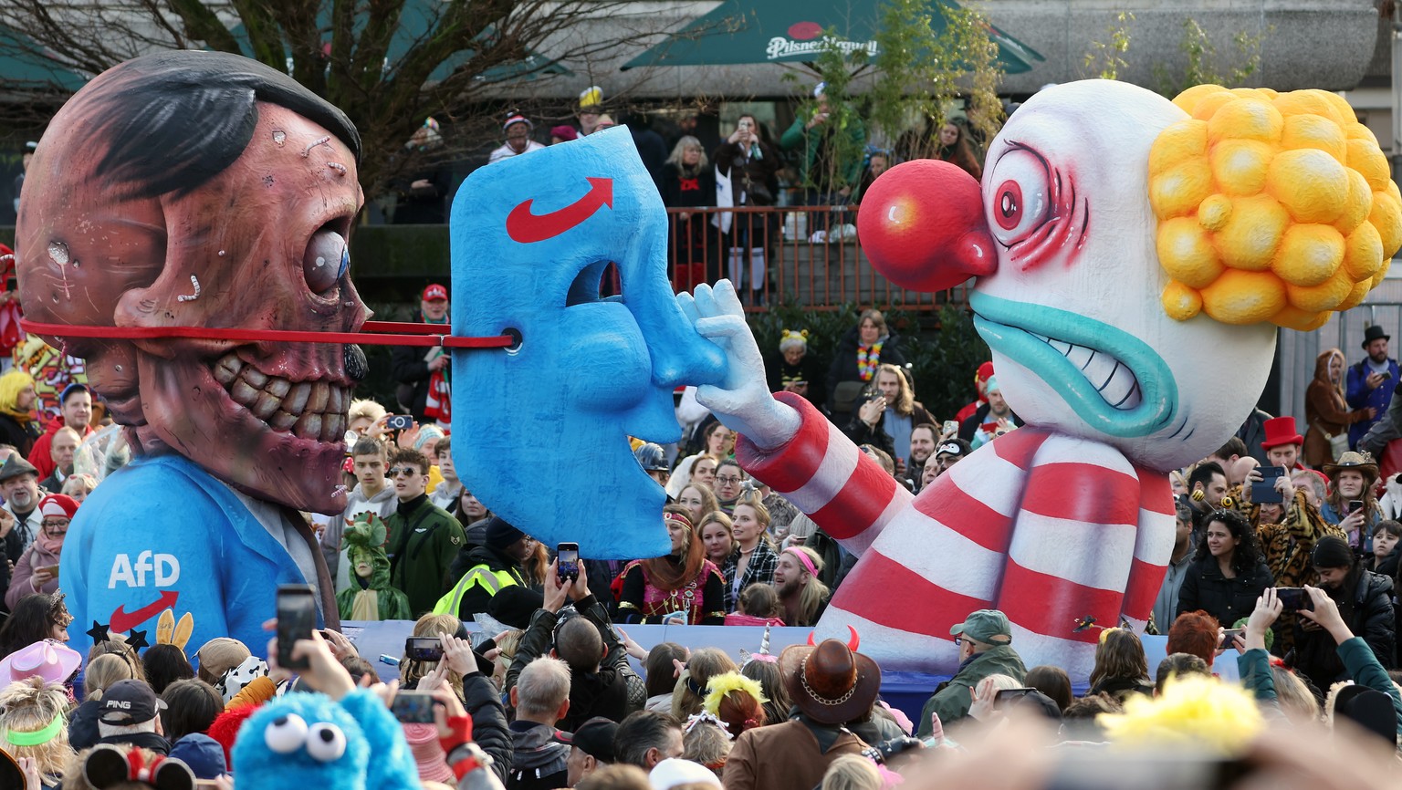 epa11147662 A carnival float depicting a clown lifting a German far-right party Alternative for Germany (AfD) mask from the face of Adolf Hitler parades during the annual Rose Monday (Rosenmontag) Car ...