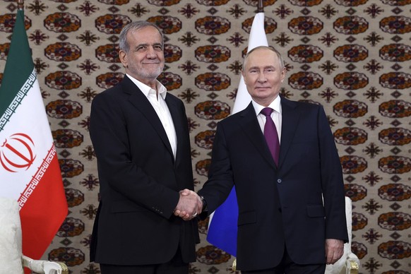 Russian President Vladimir Putin, right, and Iranian President Masoud Pezeshkian shake hands during their meeting on the sidelines of the International Forum &quot;The Interconnection of Times and Civ ...