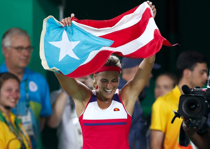 Monica Puig of Puerto Rico celebrates holding her country&#039;s flag after winning the gold medal match in the women&#039;s tennis competition at the 2016 Summer Olympics in Rio de Janeiro, Brazil, S ...