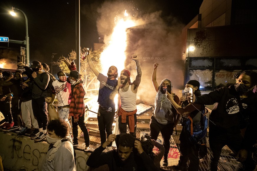 People stand outside the Minneapolis police 3rd Precinct building after fires were set at the building, Thursday, May 28, 2020, in Minneapolis, during demonstrations over the death George Floyd on Mon ...