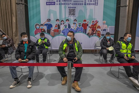 epa08938676 People wearing protective face masks wait after being vaccinated with Sinopharm vaccine against Covid-19 at a vaccination center during a government-organized media tour, in Beijing, China ...