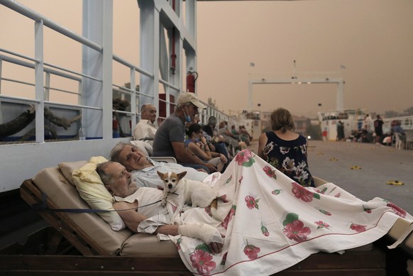 epaselect epa09406451 Georgios Liakos 89, and his wife Parisso Liakou 87, wait along with their dog Bella, on board a ferry boat to be evacuated to the mainland during a wildfire at the village of Pef ...