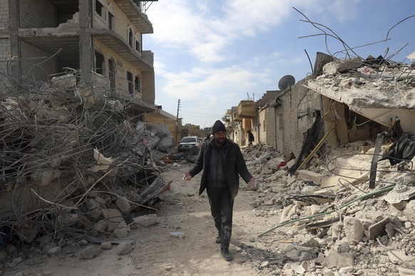 A man walks past collapsed buildings following a devastating earthquake in the town of Jinderis, Aleppo province, Syria, Tuesday, Feb. 14, 2023. The death toll from the earthquakes of Feb. 6, that str ...