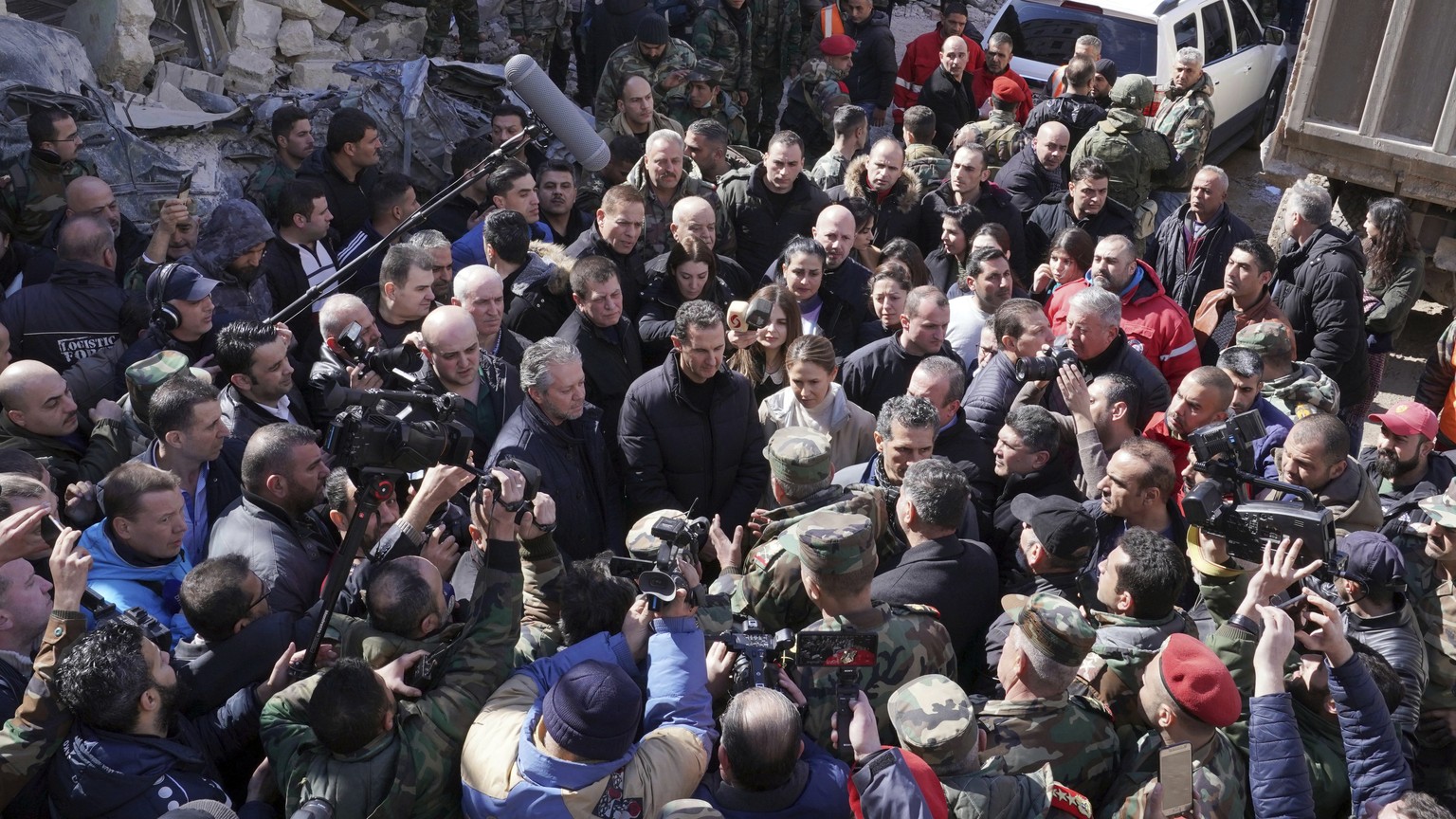 In this photo released by the official Syrian state news agency SANA, Syrian President Bashar Assad, center, and his wife Asma, visit the site of a devastating earthquake that rocked Syria and Turkey, ...