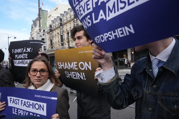 Demonstrators holds posters outside the BHV department store where fast fashion powerhouse Shein&#039;s first permanent store is set to open, Wednesday, Nov. 5, 2025 in Paris. (AP Photo/Thibault Camus ...