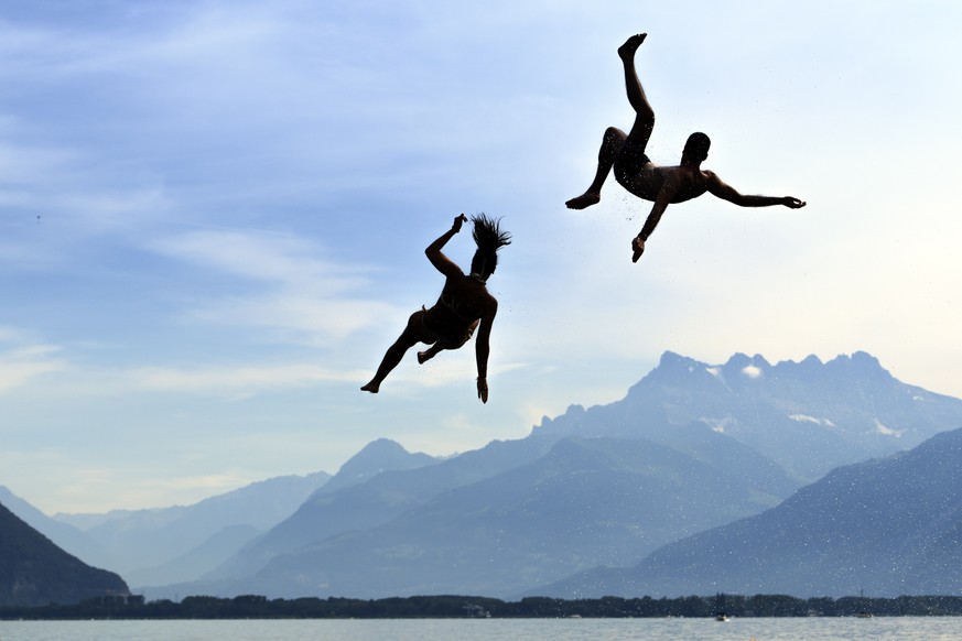 People jump into the Geneva Lake after having slipped on a water slide in front of the Swiss and French Alps mountains (Les Dents du Midi) as they enjoy the sunny and warm weather during the Summersli ...