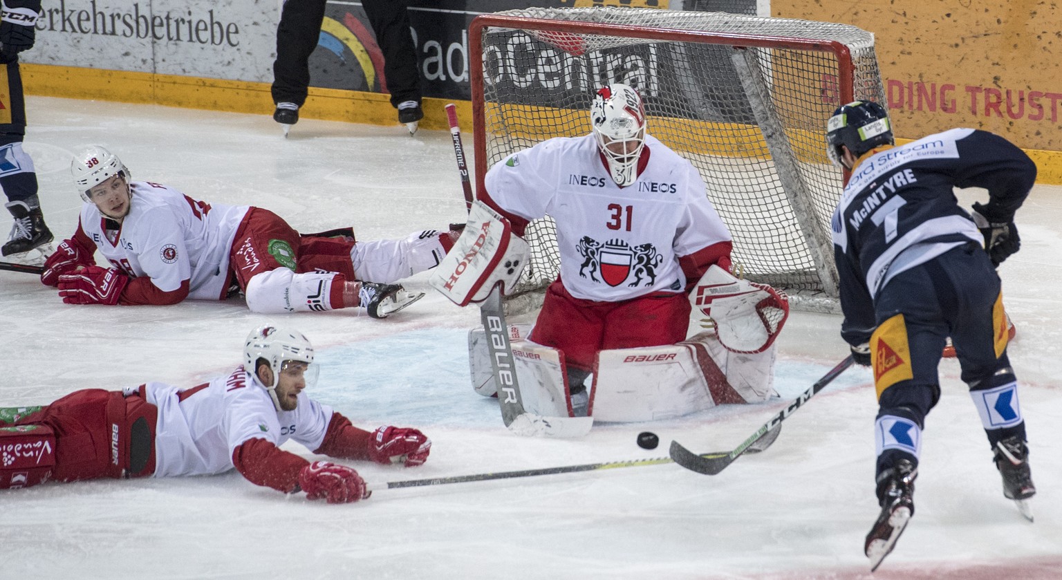 David McIntyre, rechts, von Zug im Spiel gegen Torhueter Sandro Zurkirchen, mitte, von Lausanne beim Eishockey Meisterschaftsspiel in der Qualifikation der National League zwischen dem EV Zug und dem  ...