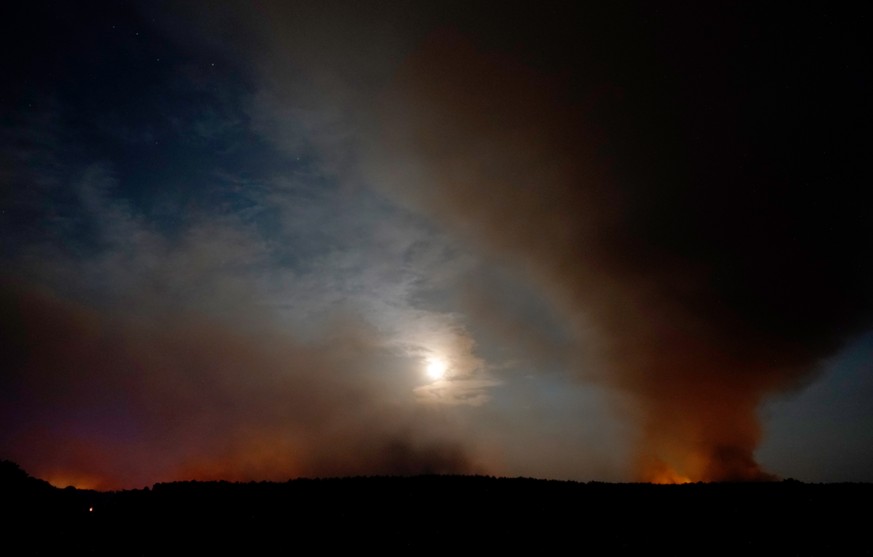 epa06967512 Long exposure photo shows the moon behind clouds of smoke during a forest fire in Karlsdorf near Treuenbrietzen in South Brandenburg, Germany, 23 August 2018. Due to a forest fire three vi ...