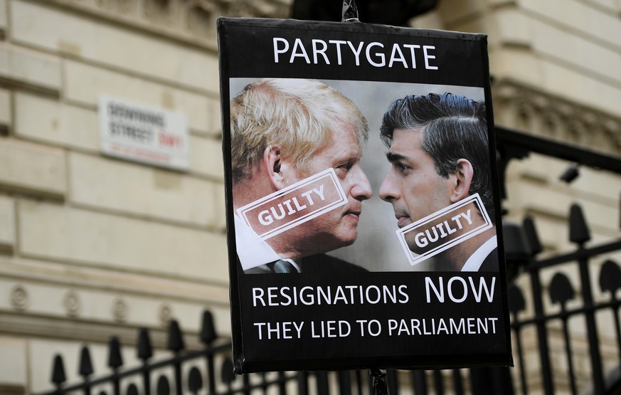epa09887686 A protester holds up a placard of British Prime Minister Boris Johnson and Chancellor Rishi Sunak outside Downing Street in London, Britain, 13 April 2022. The Metropolitan Police have han ...