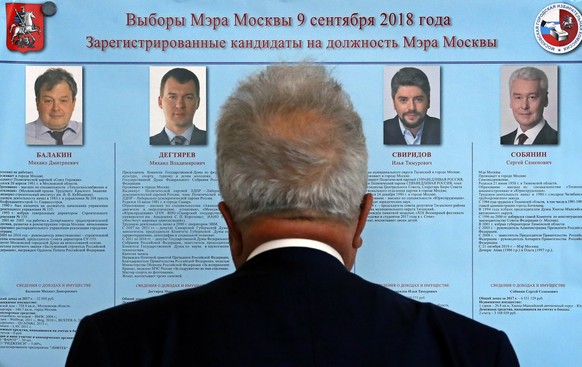 epaselect epa07007611 Russian man looks at information stand during mayor election at a polling station in Moscow, Russia, 09 September 2018. September 9 in Russia is a single day of voting. 26 subjec ...