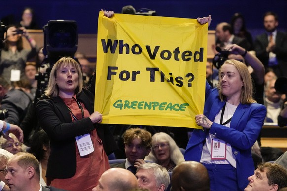Protesters hold a banner as Britain&#039;s Prime Minister Liz Truss makes a speech at the Conservative Party conference at the ICC in Birmingham, England, Wednesday, Oct. 5, 2022. (AP Photo/Kirsty Wig ...