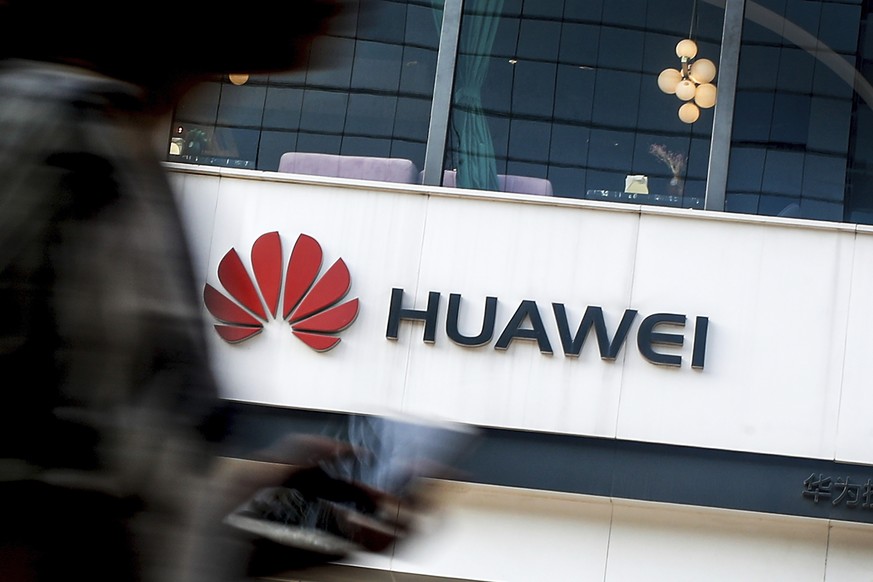 FILE - In this July 30, 2019, file photo a woman walks by a Huawei retail store in Beijing. The Trump administration has extended for 90 more days a limited reprieve on U.S. technology sales to the Ch ...