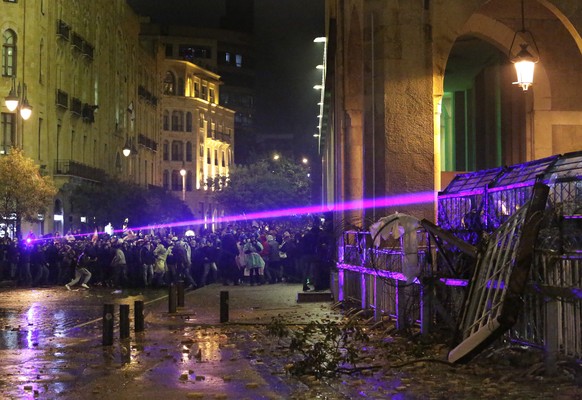 Anti-government protesters use their Laser ray lights as they clash with the riot police, during ongoing protests against the political elites who have ruled the country for decades, in Beirut, Lebano ...