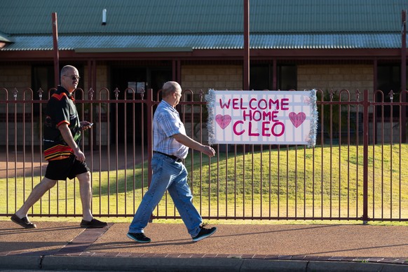 epa09566982 People walk pass a &#039;Welcome Home Cleo&#039; sign placed in support of missing girl Cleo Smith (4) who was rescued by Western Australian Police on Wednesday morning in Carnarvon, 900km ...