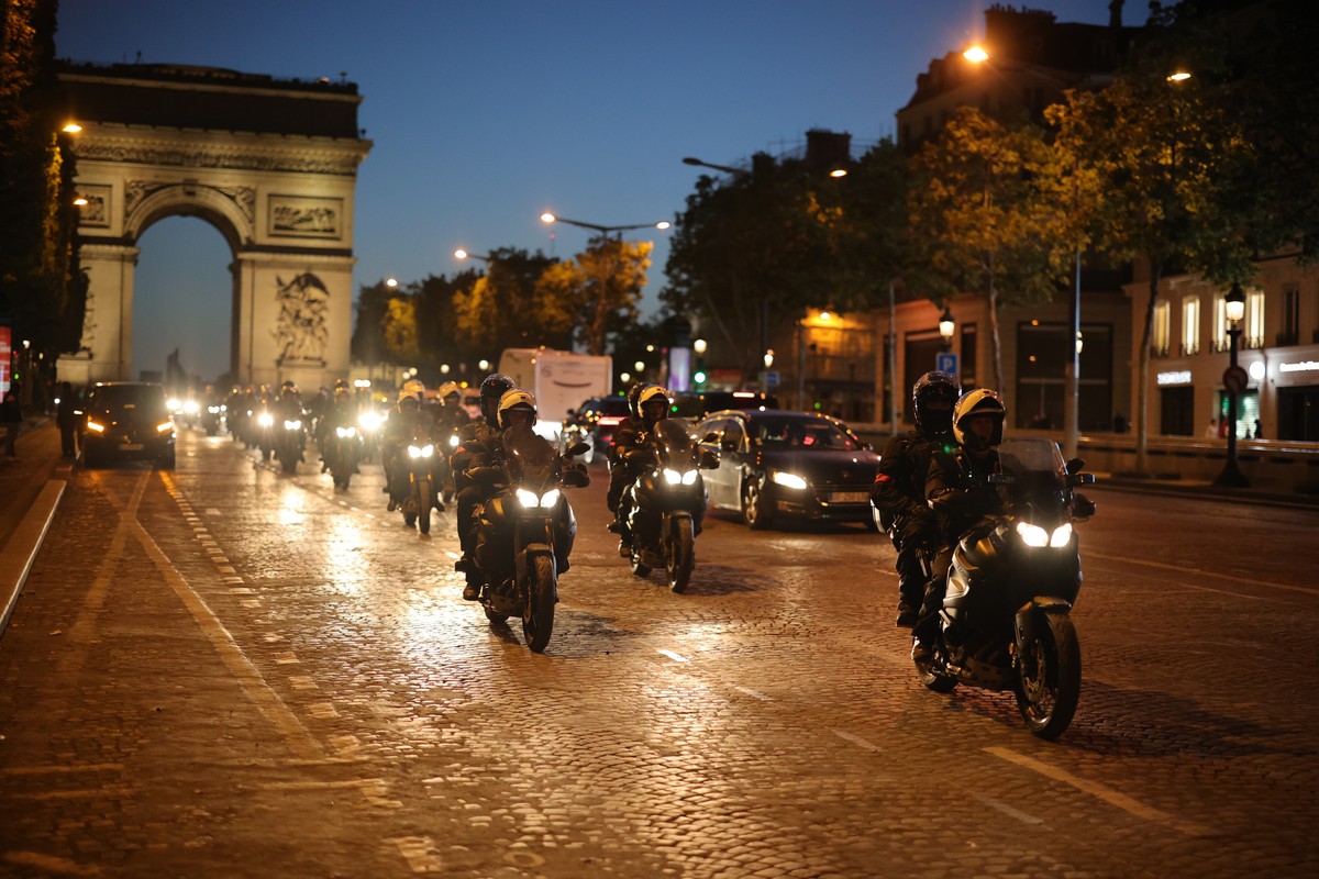 Un cortège de policiers de la brigade anti-émeute sécurise la zone devant l'Arc de triomphe samedi soir à Paris.