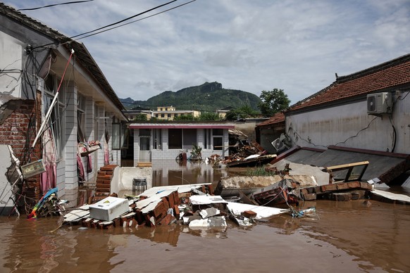epa12270996 Debris is seen in a flooded street in Taishitun, in the district of Miyun, Beijing, China, 29 July 2025. The floods brought on by the rains in past days in Beijing resulted in the deaths o ...
