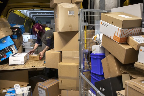 Die Paketbotin Leila Meyer fuellt am fruehen Morgen einen Lieferbus der Post mit Paketen, im Paketzentrum Haerkingen, am Mittwoch, 9. Dezember 2020, in Haerkingen. (KEYSTONE/Peter Klaunzer)