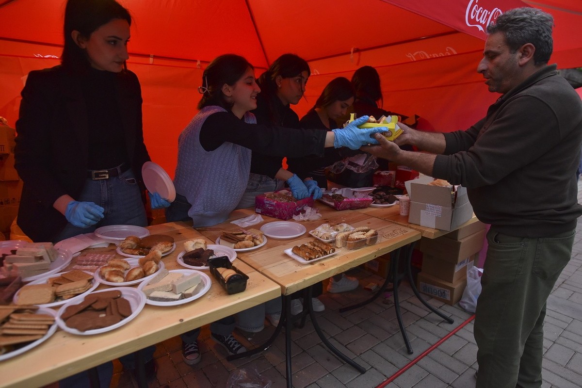 epa10884854 Volunteers distribute food for ethnic Armenians from Nagorno-Karabakh that gathered near a Red Cross registration centre in Goris, Armenia, 26 September 2023. Azerbaijan on 19 September 20 ...