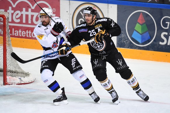 Fribourg&#039;s player Jonas Holos, left, fights for the puck with Lugano’s player Maxime Lapierre, right, during the preliminary round game of National League Swiss Championship between HC Lugano and ...