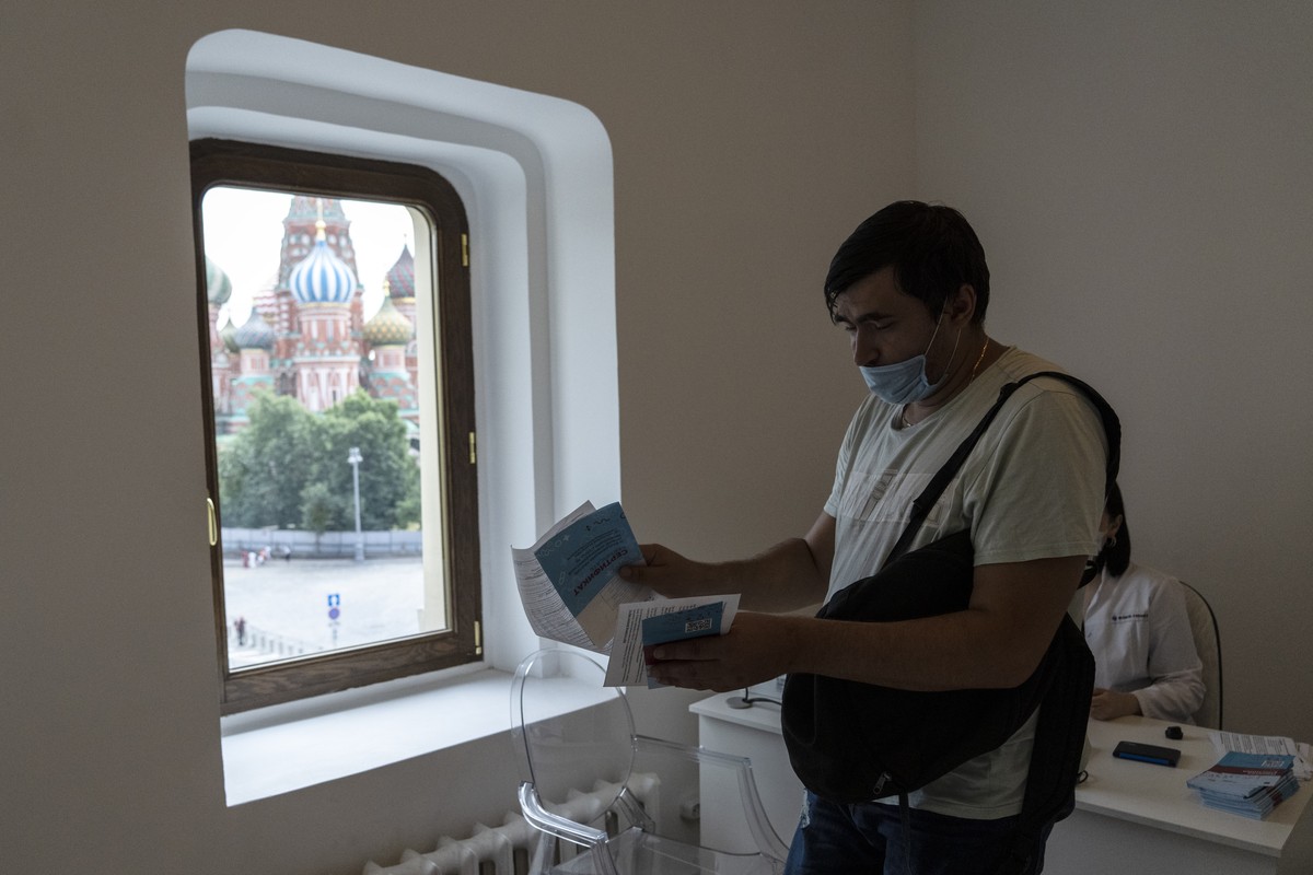 A man prepares to be vaccinated with Russia's Sputnik V coronavirus vaccine in the GUM, State Department store, as the St. Basil's Cathedral is seen in a window, in Red Square in Moscow, Rus ...