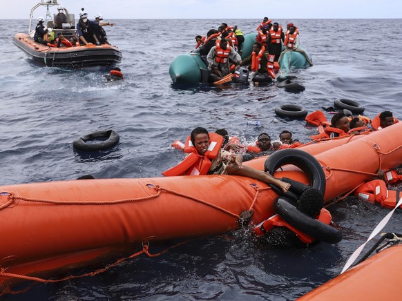 Migrants aboard a precarious rubber boat end up in water while others grab a centifloat before being rescued by a team of the Sea Watch-3, around 35 miles away from Libya, in Libyan SAR zone, Monday,  ...