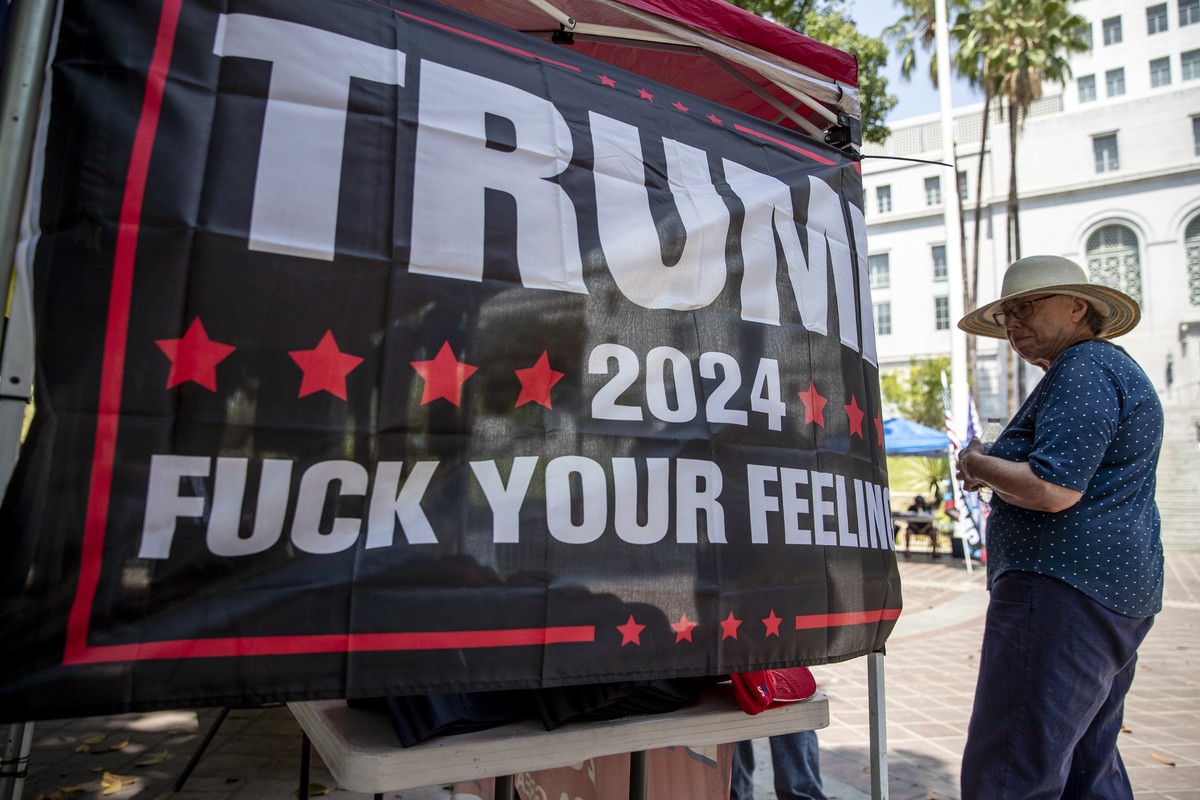 epa09414424 A demonstrator looks at a banner reading 'Trump 2024 Fuck your feelings' during an anti vaccination protest in front of the City Hall in Los Angeles, California, USA, 14 August 2 ...