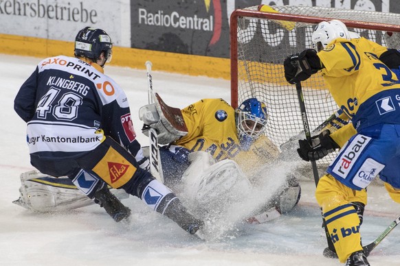 Torhueter Torhueter Joren van Pottelberghe, mitte, klaert vor Carl Klingberg, links, von Zug beim Eishockey Meisterschaftsspiel in der Qualifikation der National League zwischen dem EV Zug und dem HC  ...