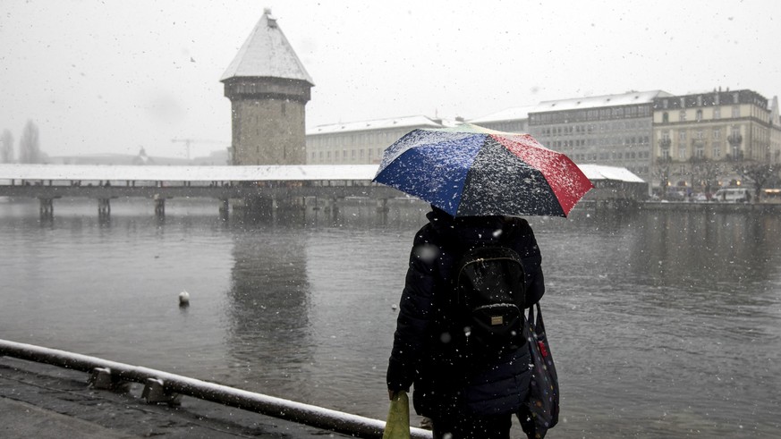 Eine Frau steht mit einem Regenschirm bei Schneefall vor der Kapellbruecke in Luzern, am Samstag, 5. Januar 2018. (KEYSTONE/Alexandra Wey)