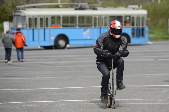 Un homme casque test un velo trotinette devant un bus des Transports publics de la region lausannoise, TL, lors de la competition Bus d&#039;Or ce samedi 5 avril 2014 a Lausanne. 12 conducteurs des TL ...