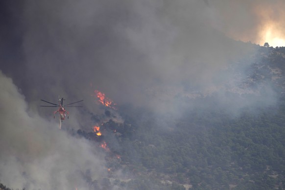 A firefighter helicopter flies toward a wildfire on Parnitha mountain, in Acharnes, northern Athens, Greece, Wednesday, Aug. 23, 2023. Water-dropping planes from several European countries joined hund ...