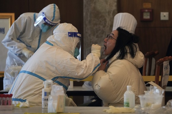 A medical worker collects a sample from a reporter taking part in the Beijing Winter Olympics torch relay activities at a coronavirus test site in Beijing, Wednesday, Feb. 2, 2022. With more than 30 n ...