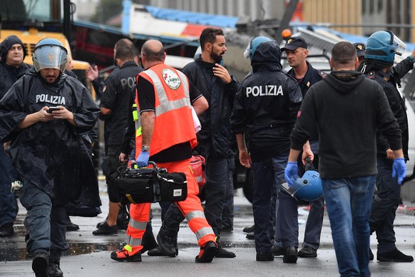 epa06948881 Rescuers at the site of the collapsed bridge in Genoa, Italy, 14 August 2018. A large section of the Morandi viaduct upon which the A10 motorway runs collapsed in Genoa on Tuesday. Both si ...