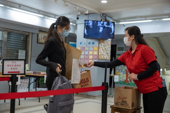 epa08380992 A student has her documents checked before sitting for the Diploma of Secondary Education (DSE) exams in Hong Kong, China, 24 April 2020. Temperature checks and social distancing measures  ...