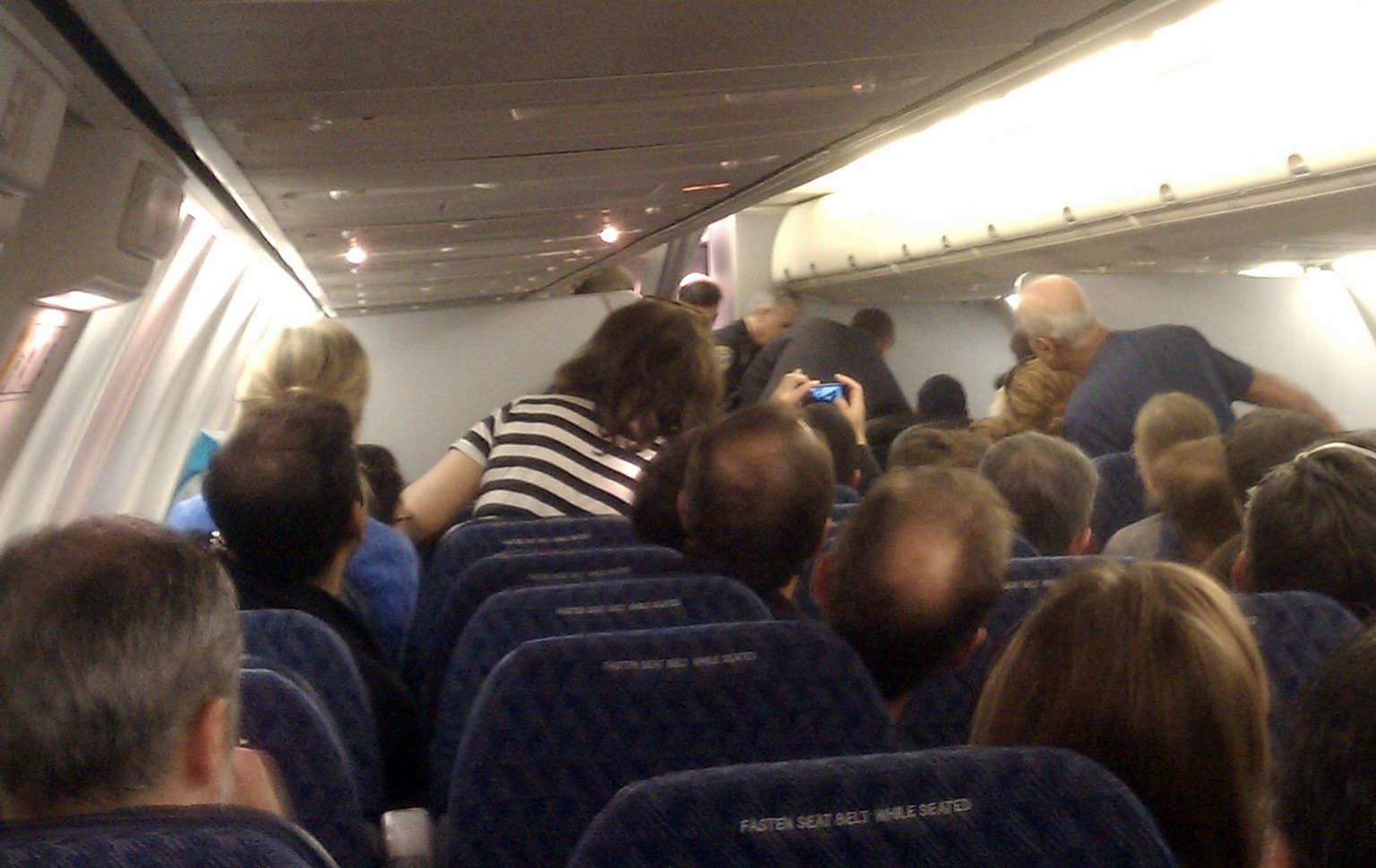 In this image captured by citizen journalist Andrew Wai, passengers, top right, subdue a man identified as Rageh Almurisi (not seen) on board an American Airlines flight headed to San Francisco, Sunda ...