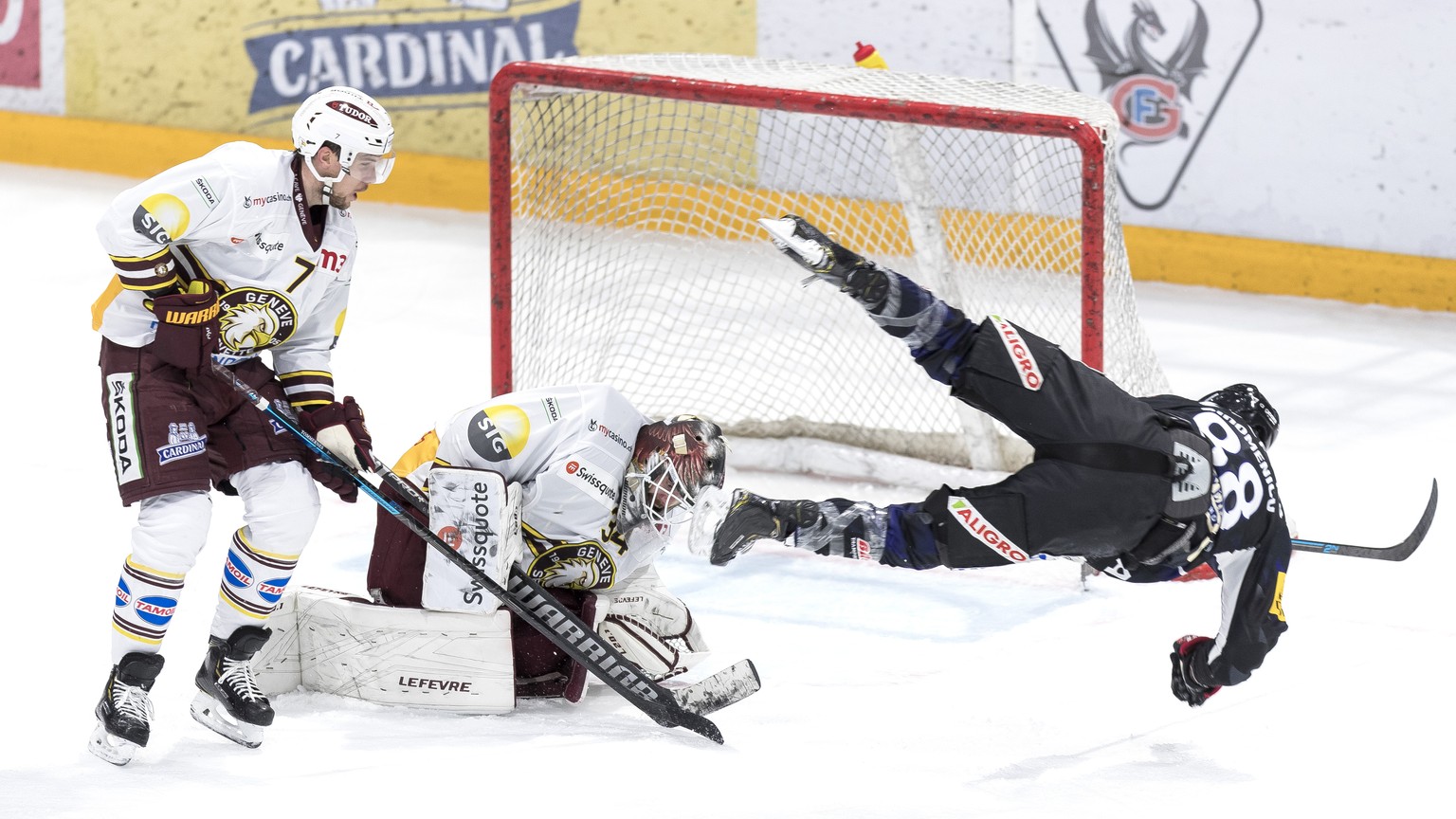 Le defenseur genevois Henrik Toemmernes, gauche, et le gardien genevois Gauthier Descloux, centre, luttent pour le puck avec l&#039;attaquant fribourgeois Christopher DiDomenico, droite, lors du match ...