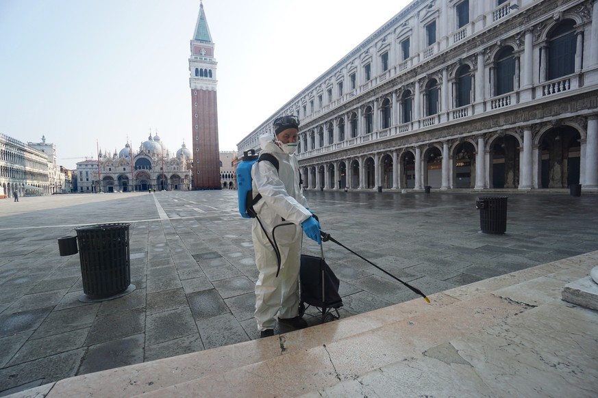 epa08288286 A sanitation employee disinfects the historical Marciana area of Venice, Italy, 12 March 2020. Venice's waste management provider Veritas is set to close down all waste collection centers  ...