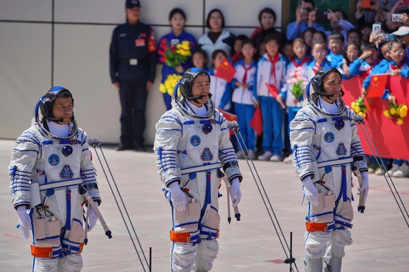 FILE - Chinese astronaut for the Shenzhou 20 mission, Chen Dong, center, speaks next to his comrades Chen Zhongrui, right, and Wang Jie as they attend a send-off ceremony for their manned space missio ...