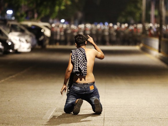 epa09035619 A demonstrator protests against the military coup while riot police advance on a street as tensions rise in Yangon, Myanmar, 25 February 2021. Anti-coup demonstrations continued amid regio ...