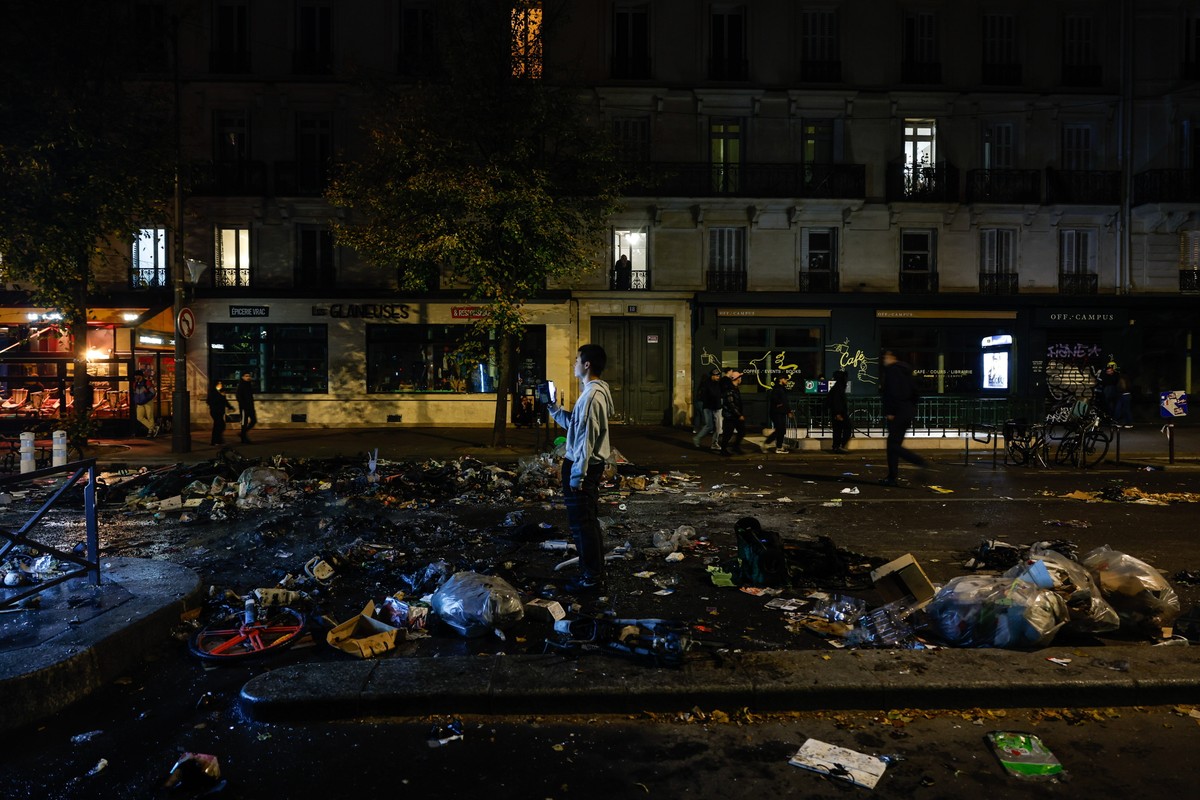 epa13314541 People pass next to debris remaining in the street as clashes between riot police and demonstrators continue for the second day during nationwide protests against the high cost of living i ...