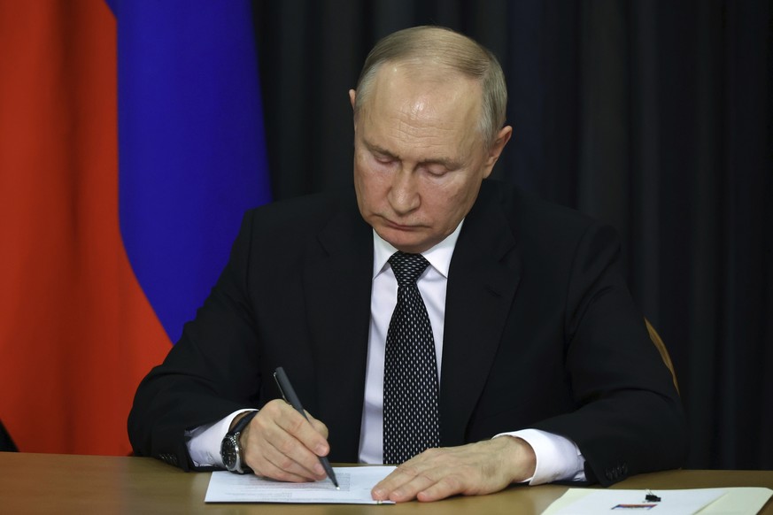 Russian President Vladimir Putin writes down notes as he attends a plenary session of the World Russian People&#039;s Council, dedicated to the 30th anniversary of the founding of the organisation, vi ...