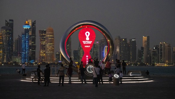 People gather around the official countdown clock showing remaining time until the kick-off of the World Cup 2022, in Doha, Qatar, Thursday, Nov. 25, 2021. The World Cup is due to start in November 20 ...