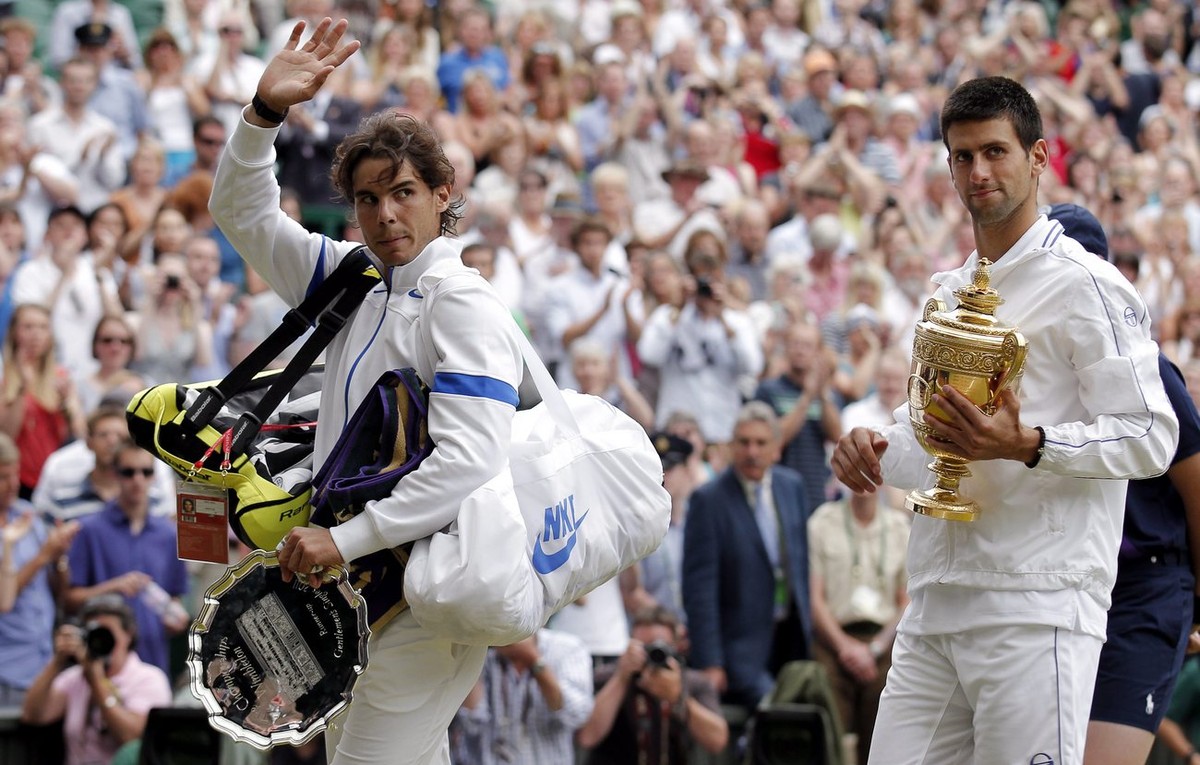 epa02808667 Novak Djokovic of Serbia (R) holds the championship trophy following his victory over Rafael Nadal of Spain (L) in the men's singles final of the Wimbledon Championships at the All En ...