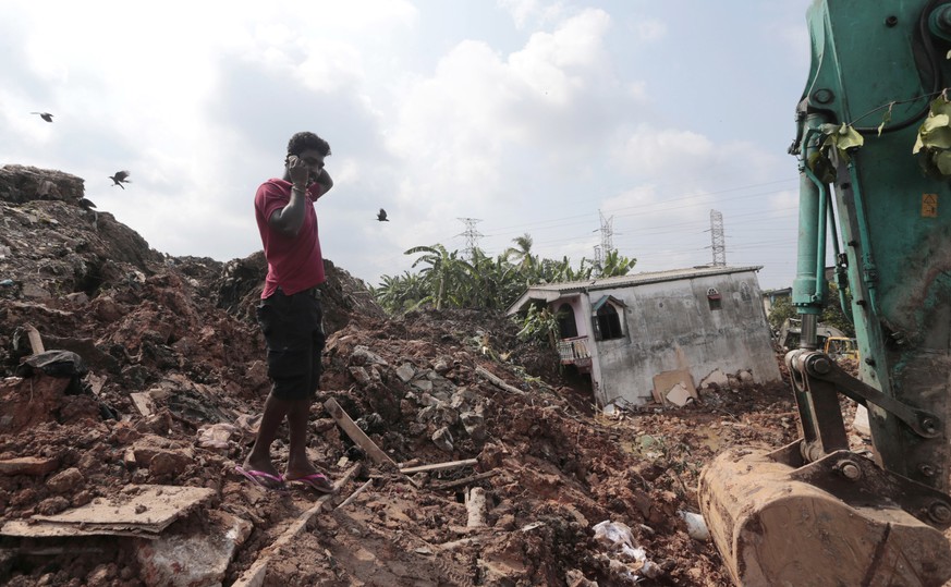 A Sri Lankan man speaks on his mobile phone at the site of buried houses in a collapse of a garbage dump in Meetotamulla, on the outskirts of Colombo, Sri Lanka, Saturday, April 15, 2017. A part of th ...