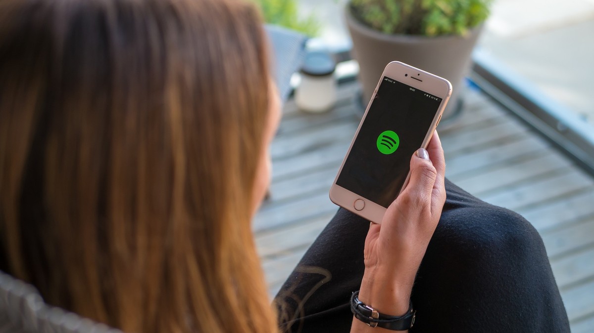 Frau hält Smartphone mit Spotify-Logo auf dem Display.