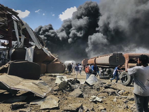 FILE - People are seen in front of clouds of black smoke from fires in the aftermath at the scene of an airstrike in Mekele, the capital of the Tigray region of northern Ethiopia on Oct. 20, 2021. Pri ...