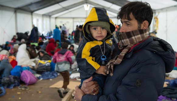 epa05007361 A Syrian father and his one-year-old son Abel wait to cross the border into Germany at emergency accommodation near the border town of Hanging, Austria, 02 November 2015. German Chancellor ...