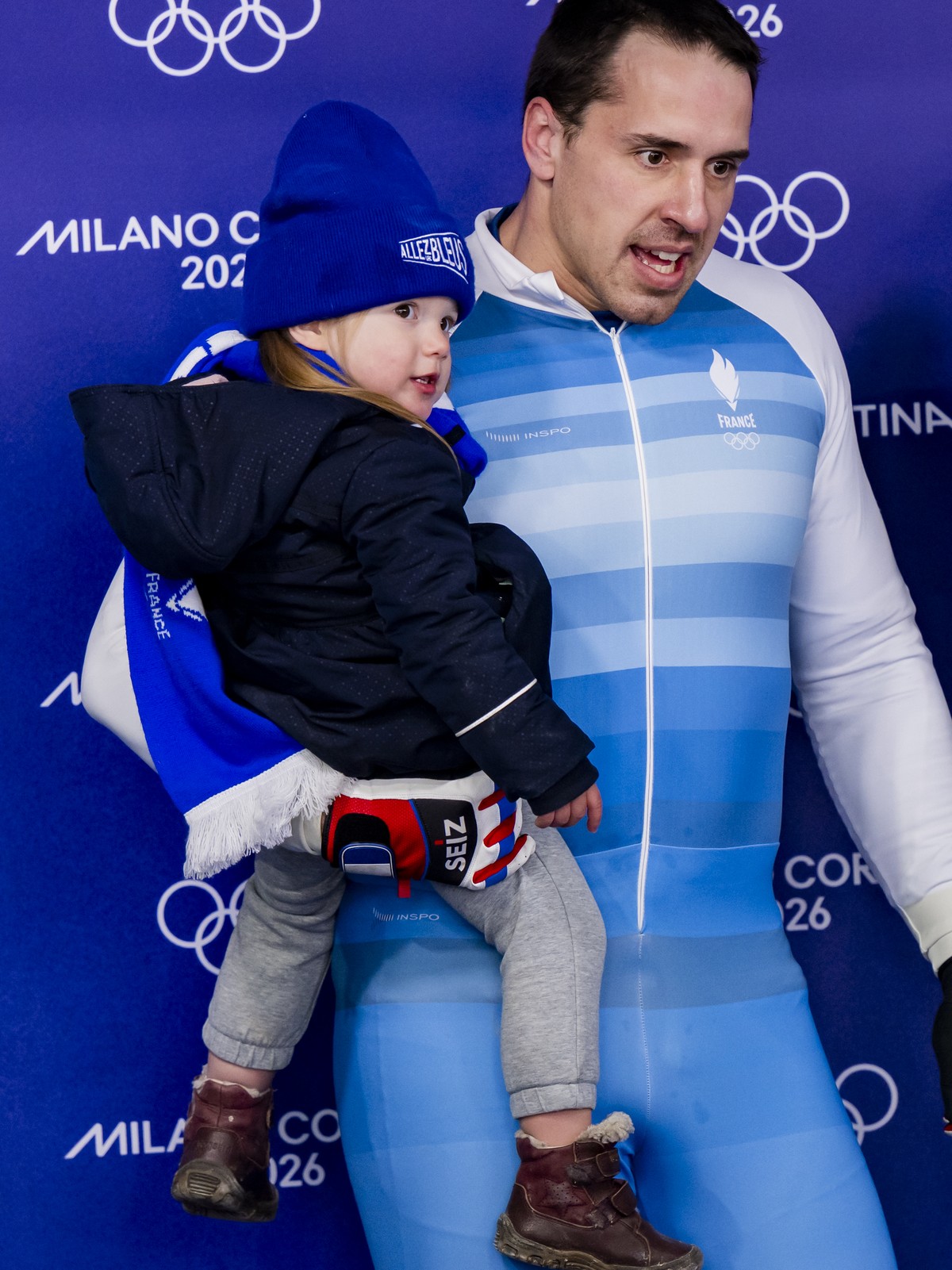 Pilot Romain Heinrich of France reacts in the finish area with Noelie, the girl he has with the pusher Nadja Pasternack of Switzerland during the men's two man bobsled heat 2 at the 2026 Olympic  ...