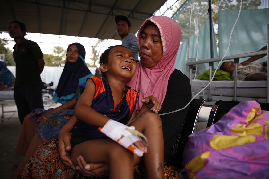 epa06940275 A mother holds her six-years old son, Lalu Azham at an emergency hospital in Tanjung northern Lombok, West Nusa Tenggara, Indonesia, 10 August 2018. According to media reports, a 7.0 magni ...