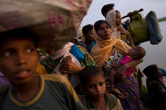 A Rohingya Muslim woman carries an infant child and walks with a group after crossing the border from Myanmar into Bangladesh, near Palong Khali, Bangladesh, Wednesday, Nov. 1, 2017. In a scene that&# ...