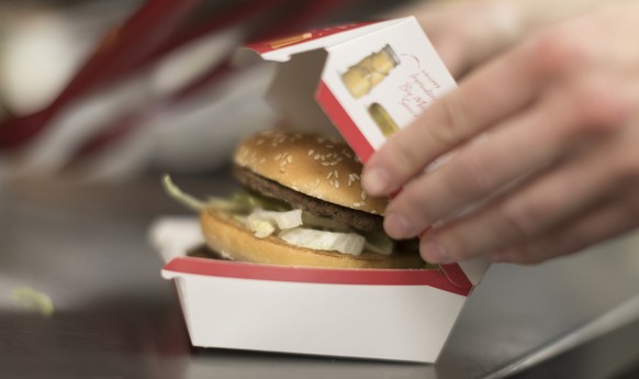 ZUM FASTFOOD-RESTAURANT MCDONALD&#039;S STELLEN WIR IHNEN HEUTE, MITTWOCH, 8. MAERZ 2017, FOLGENDES BILDMATERIAL ZUR VERFUEGUNG --- An employee closes a burger box in the kitchen of a McDonald&#039;s  ...